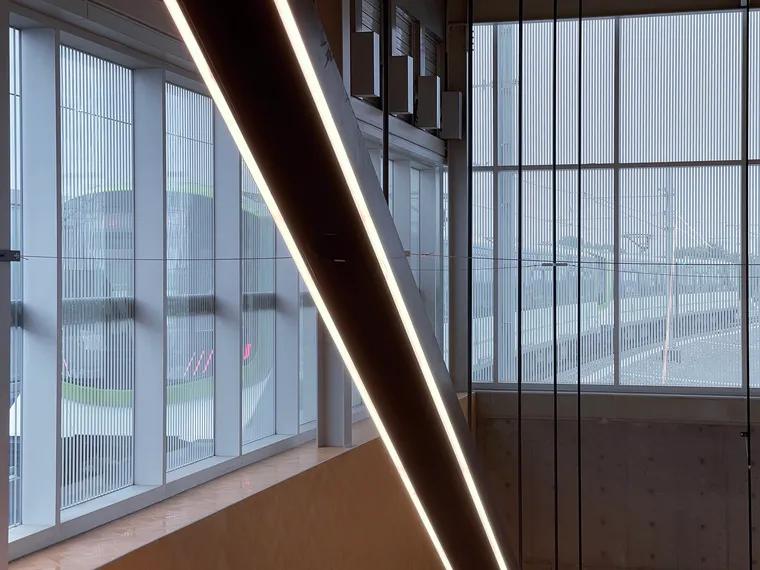 REM station with diagonal escalator light & train behind screened windows