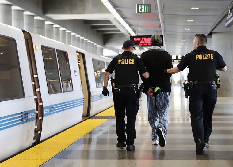 San Francisco BART station platform showing Police leading cuffed suspect