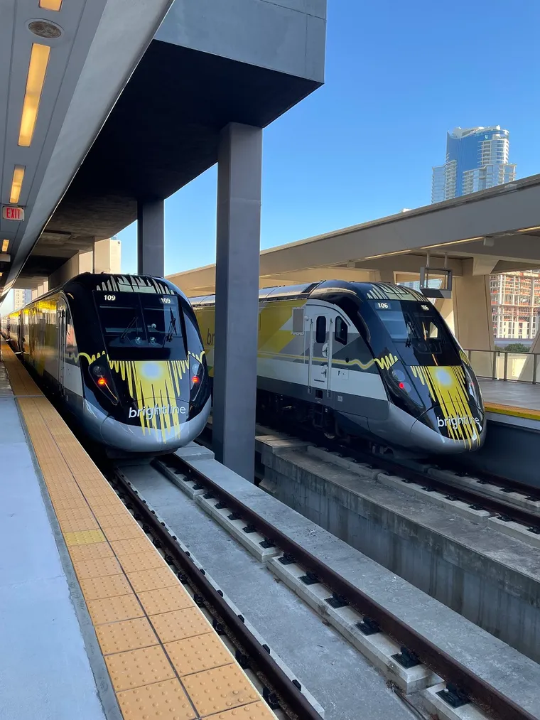 Sleek Brightline trains in station, side by side, showing angled noses