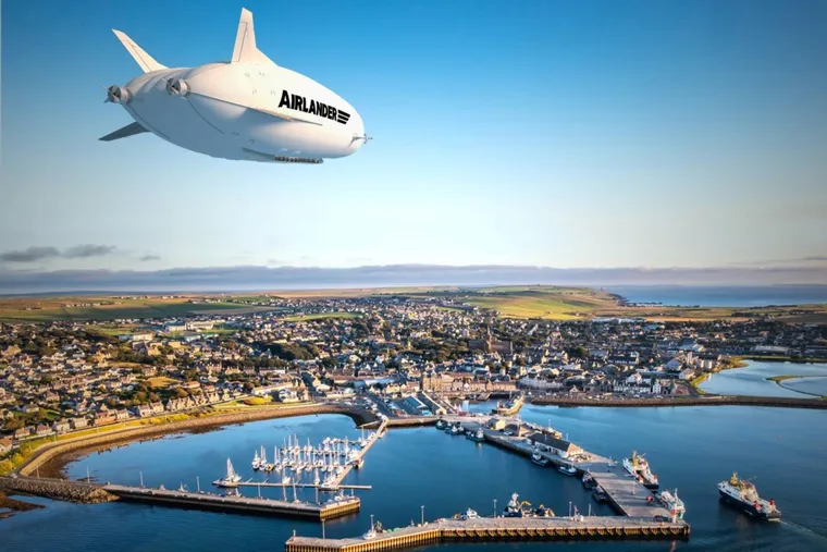 Render of a Hybrid Air Vehicles Airlander 10 airship over a small island town and harbour