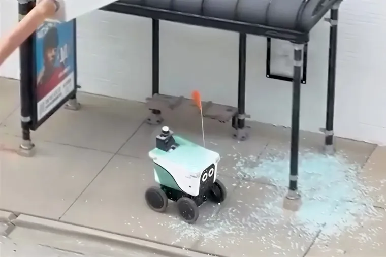Small delivery robot smashes bus stop glass, shards on ground. Future Adam Curtis